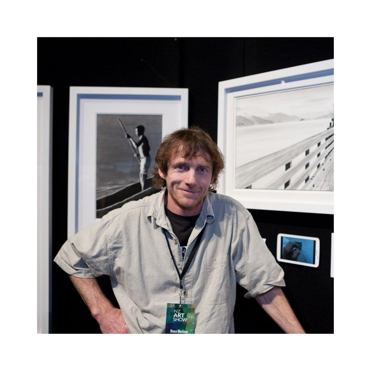 Profile picture of artist Bruce Mortimer in front of two of his pencil drawings at a art show