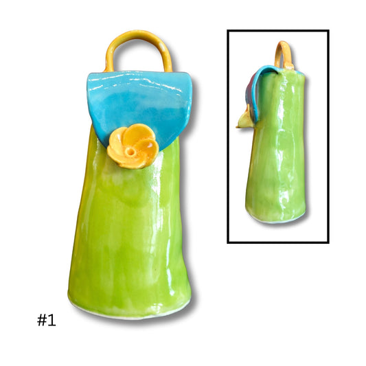 Green ceramic purse with blue top and yellow handle on a white background