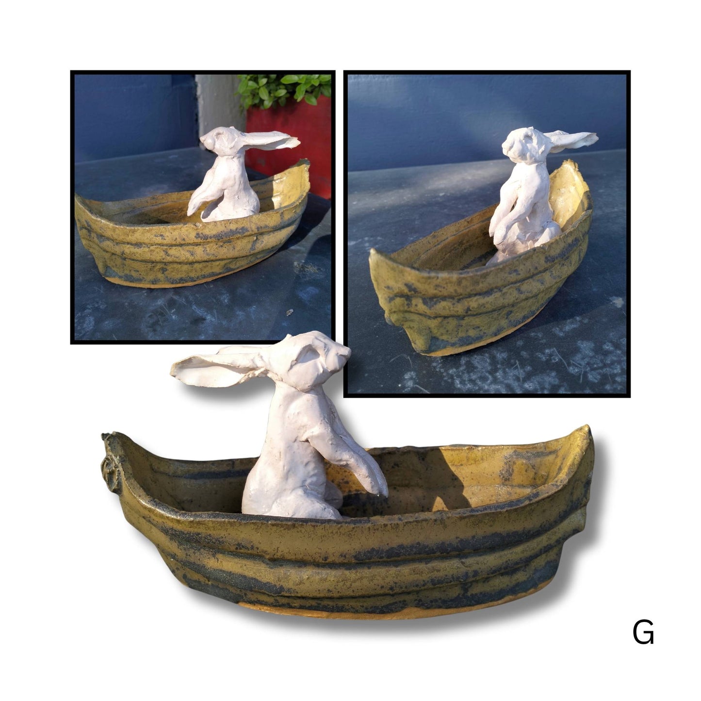 Whimsical Drifter sculpture with front paws tucked up close, seated in a soft brown ceramic boat, crafted by Kylie Matheson.