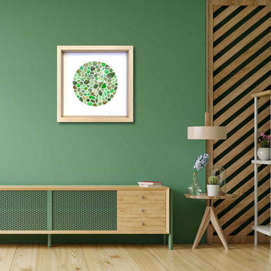 Framed green circular sea glass art in soft coastal tones in stylish lounge setting.  Artwork by Steffi Tregenna