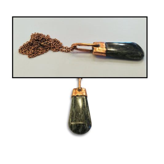 Close-up view of the handcrafted greenstone pendant with copper detailing, highlighting the stone’s soft green tones and the artist’s textured copperwork.