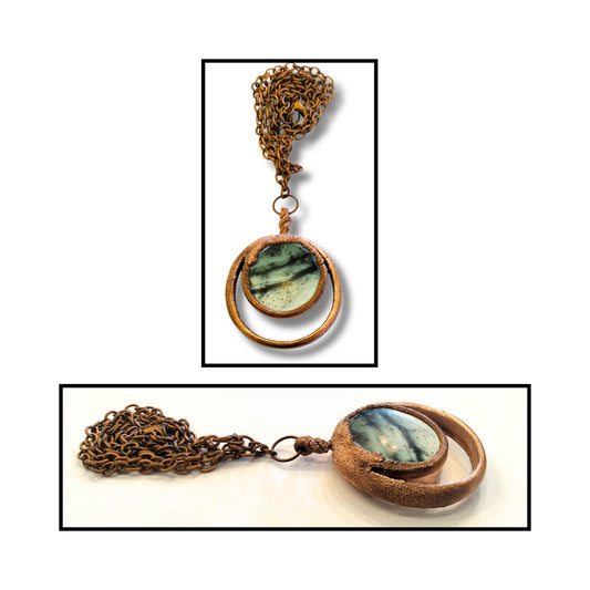 Close-up of circular greenstone with brushed copper bezel and sculptural outer ring.