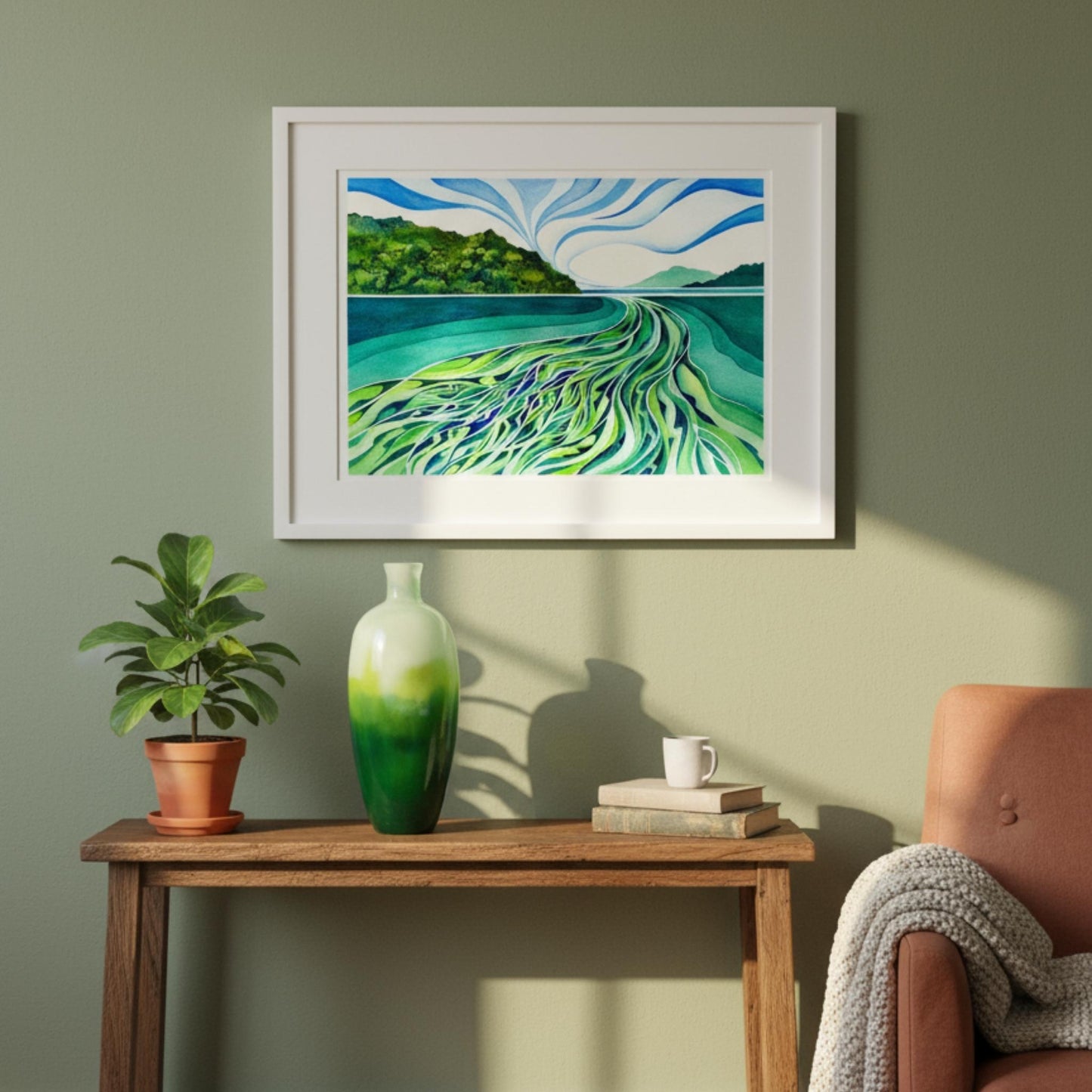 Framed artwork of a landscape with water and mountains on a wall above a wooden table with decor items.