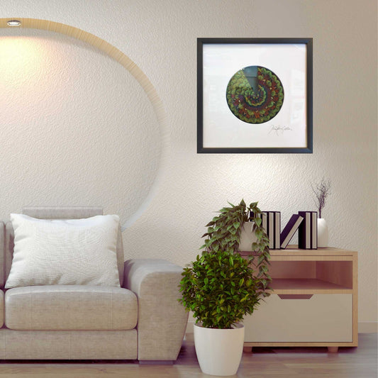 Living room with a framed circular mandala  artwork made from feathers  on the wall, a sofa, and a potted plant.