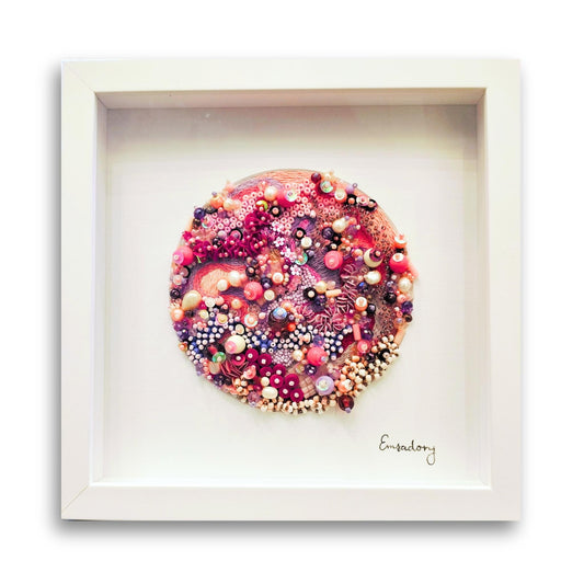 Framed artwork of soft pinks and cream beaded embroidery by artist Emily Richardson on a white background