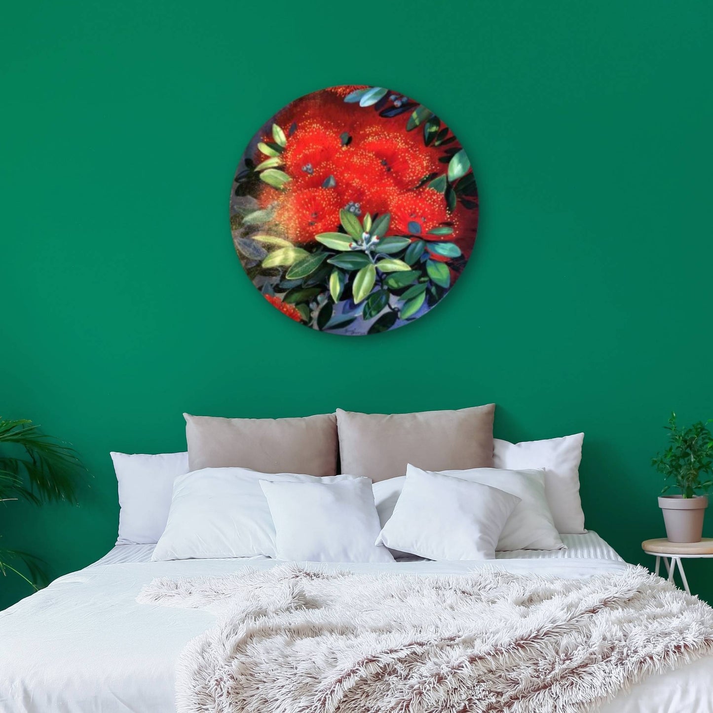Round painting of pohutukawa flowers on a green wall above a bed.