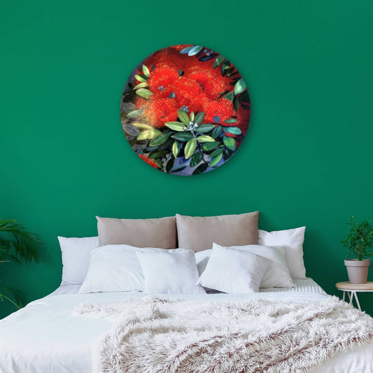 Round painting of pohutukawa flowers on a green wall above a bed.