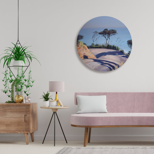 Living room with pink sofa, round wall art of a painting of the road to Anawhata beach and decorative items.