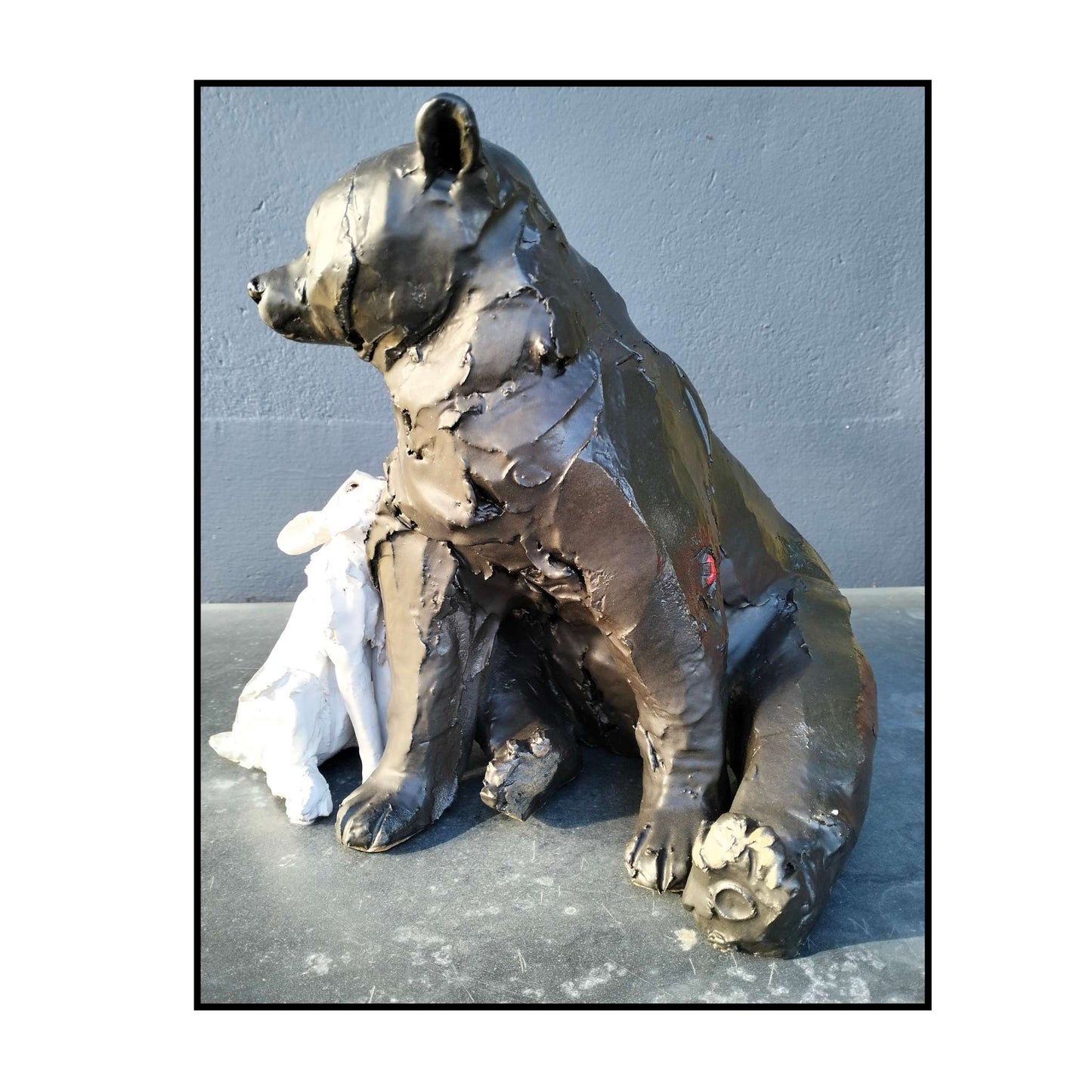 Hand-sculpted ceramic bear and rabbit titled "Secret Crush" by Kylie Matheson – a tender moment captured in clay, full view from right side showing signature red arrow