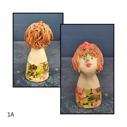 Hand-sculpted ceramic figure with blue hair and a mustard dress, hands folded thoughtfully, full of quiet personality.