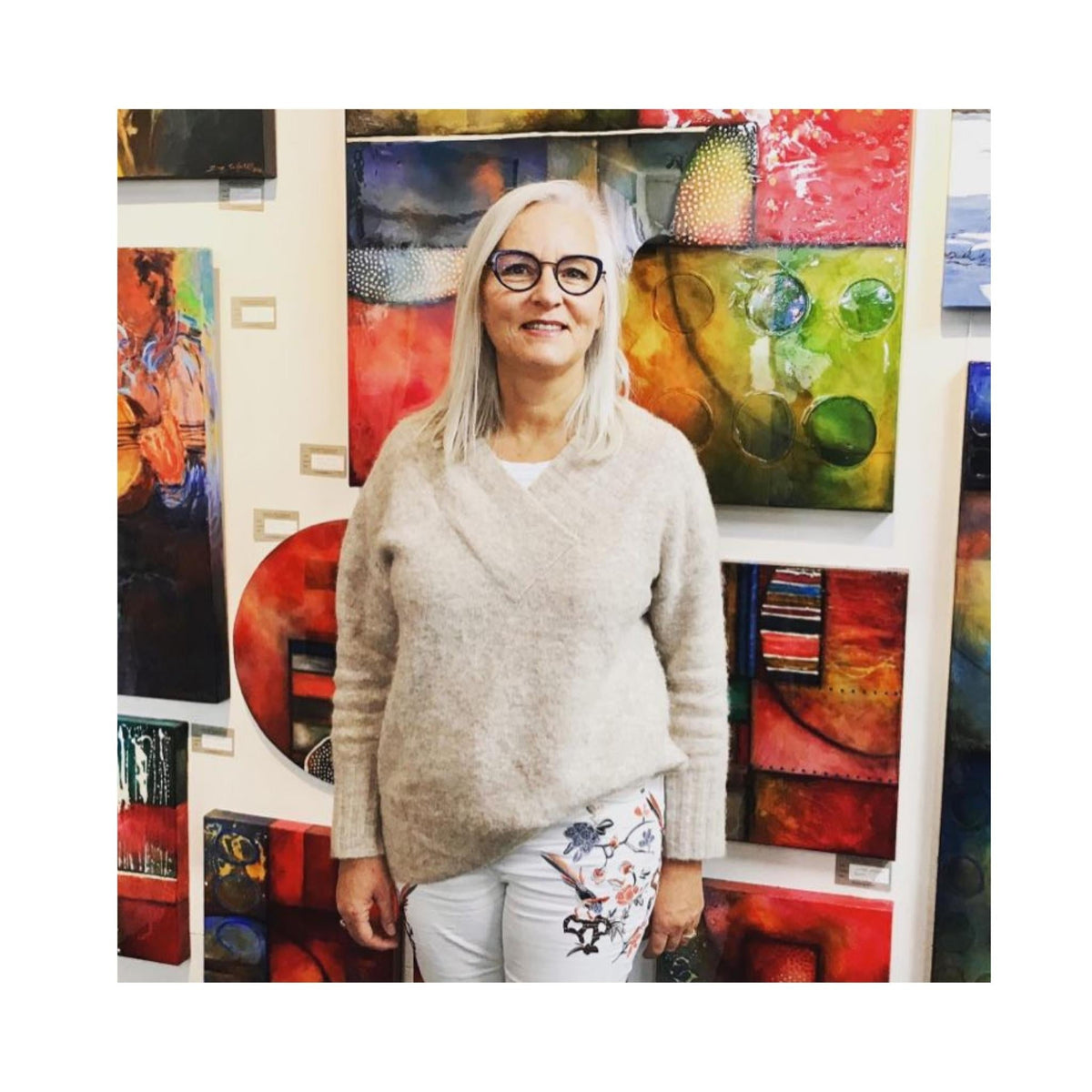 Artist Clare Wilcox standing in gallery in front of her paintings