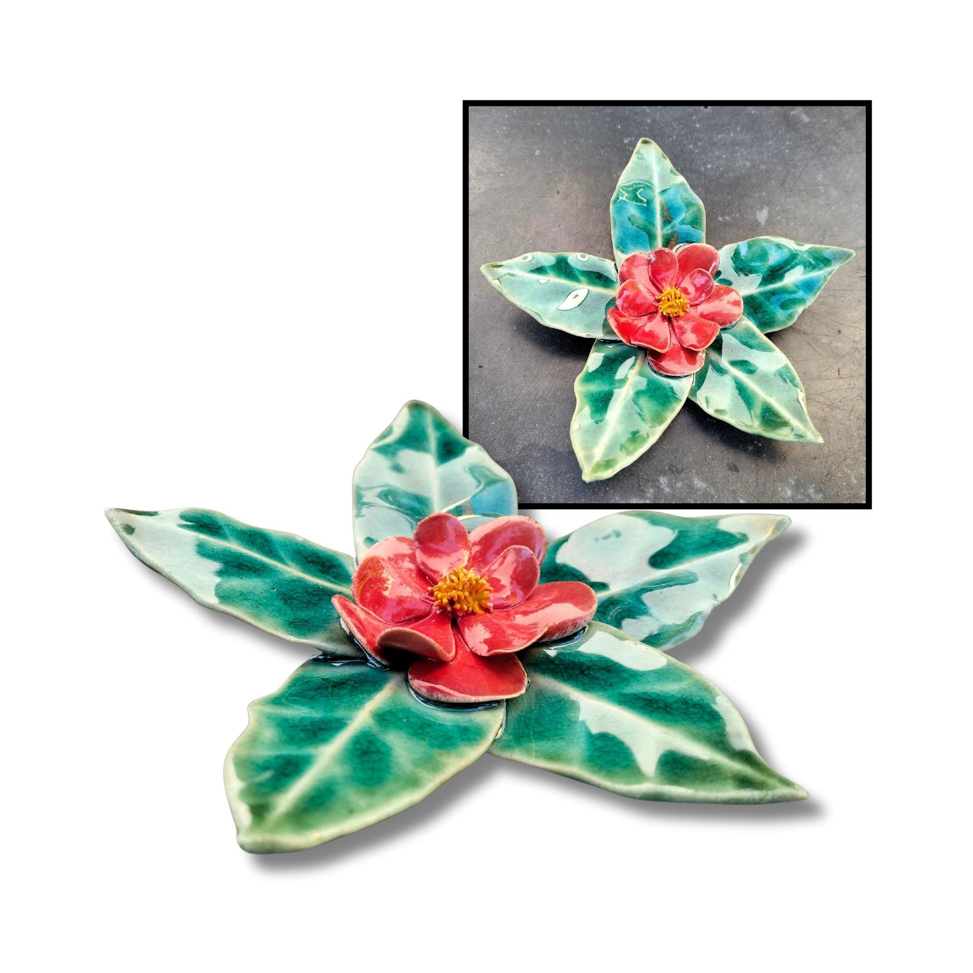 Red camellia flower sculpture with shiny glaze and leaf-shaped base.