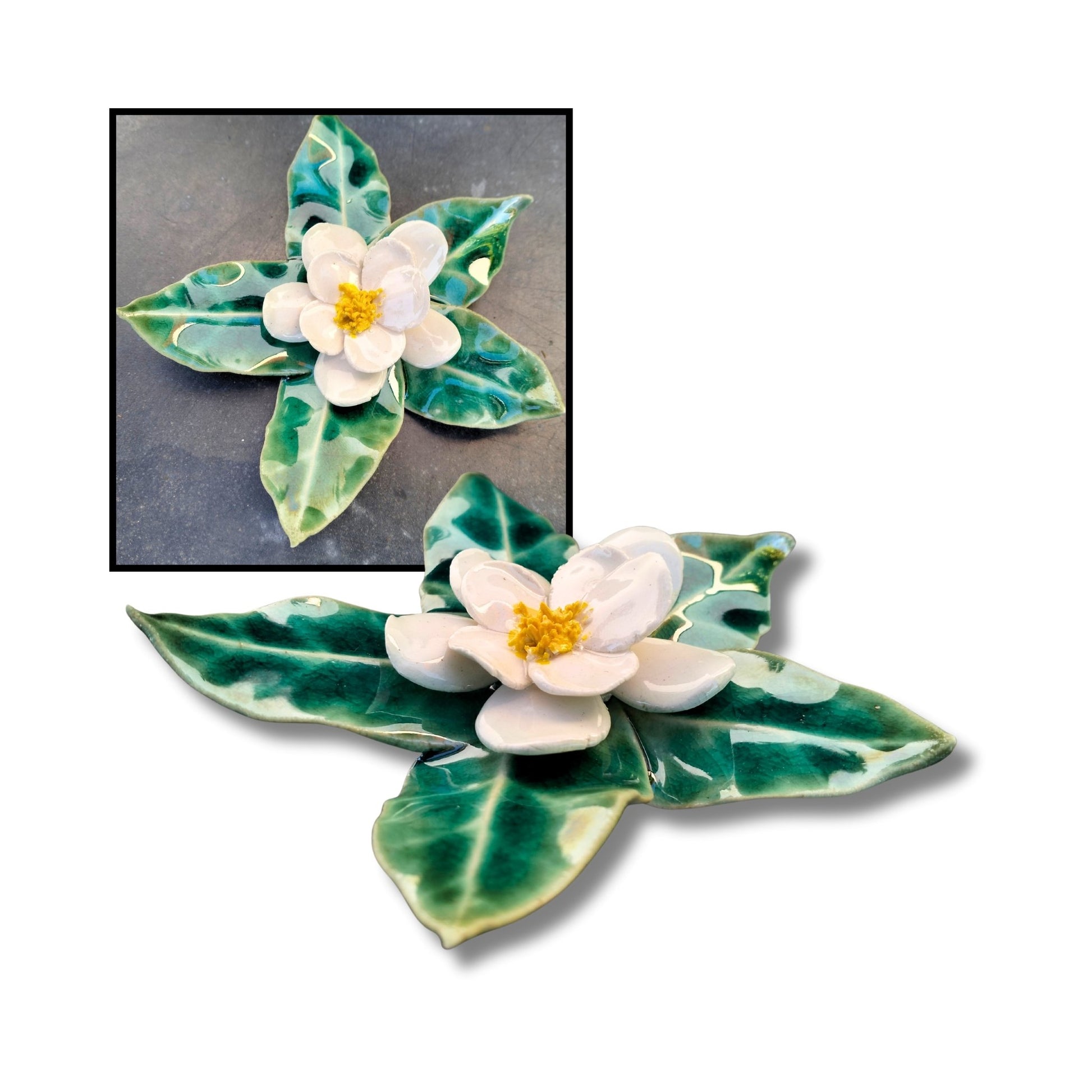 White camellia ceramic wall piece on green sculpted leaf base, glossy finish.

