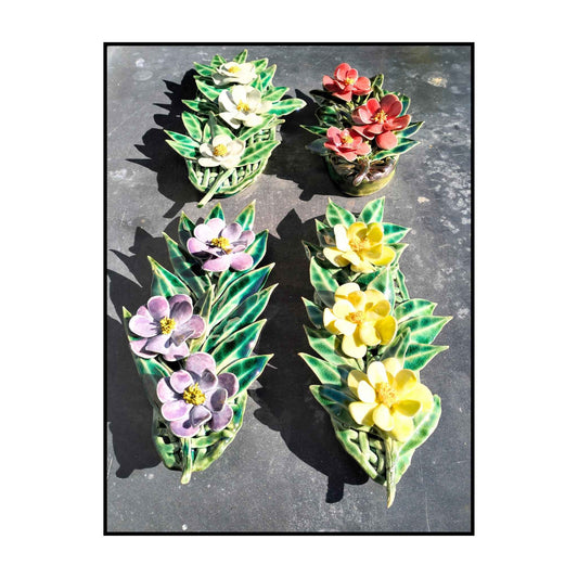 Four handmade triple camellia ceramic wall pieces by Tom Somerville in red, yellow, blue, and purple.