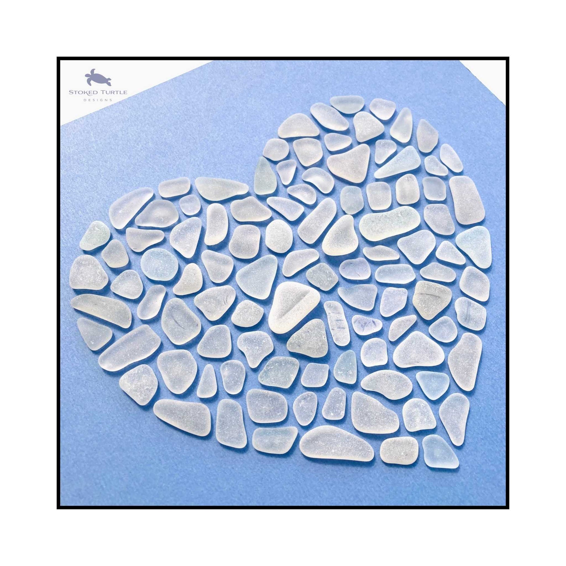 Close-up of naturally tumbled sea glass pieces forming heart shape showing frosted texture and organic forms




