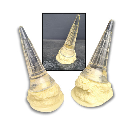 A playful acrylic sculpture of a fallen vanilla ice cream with a clear cone pointing upwards and creamy white melt puddling below.