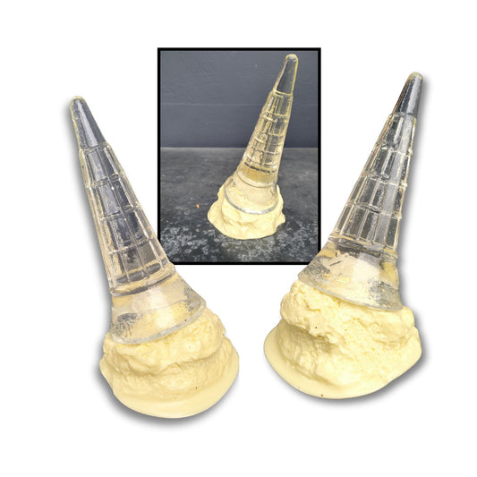 A playful acrylic sculpture of a fallen vanilla ice cream with a clear cone pointing upwards and creamy white melt puddling below.