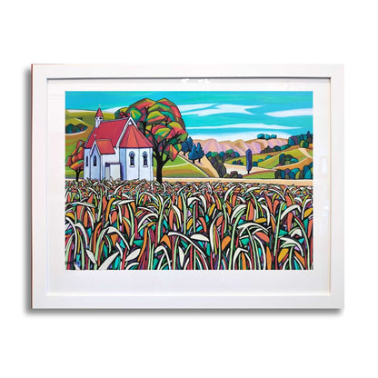 Framed artwork of a colorful landscape with the Waimarama Church and cornfield, by artist Helena Verhaaren