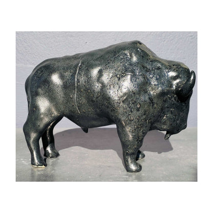 Handmade ceramic buffalo sculpture by Storm Davenport with smooth contours and a black glaze showing green and earthy brown tones.