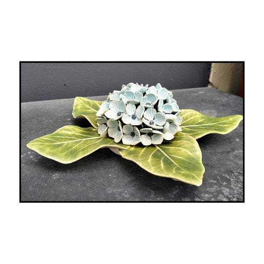 Three-dimensional ceramic Hydrangea Wall Hanging by Tom Somerville with pale blue flower cluster and glossy green leaves
