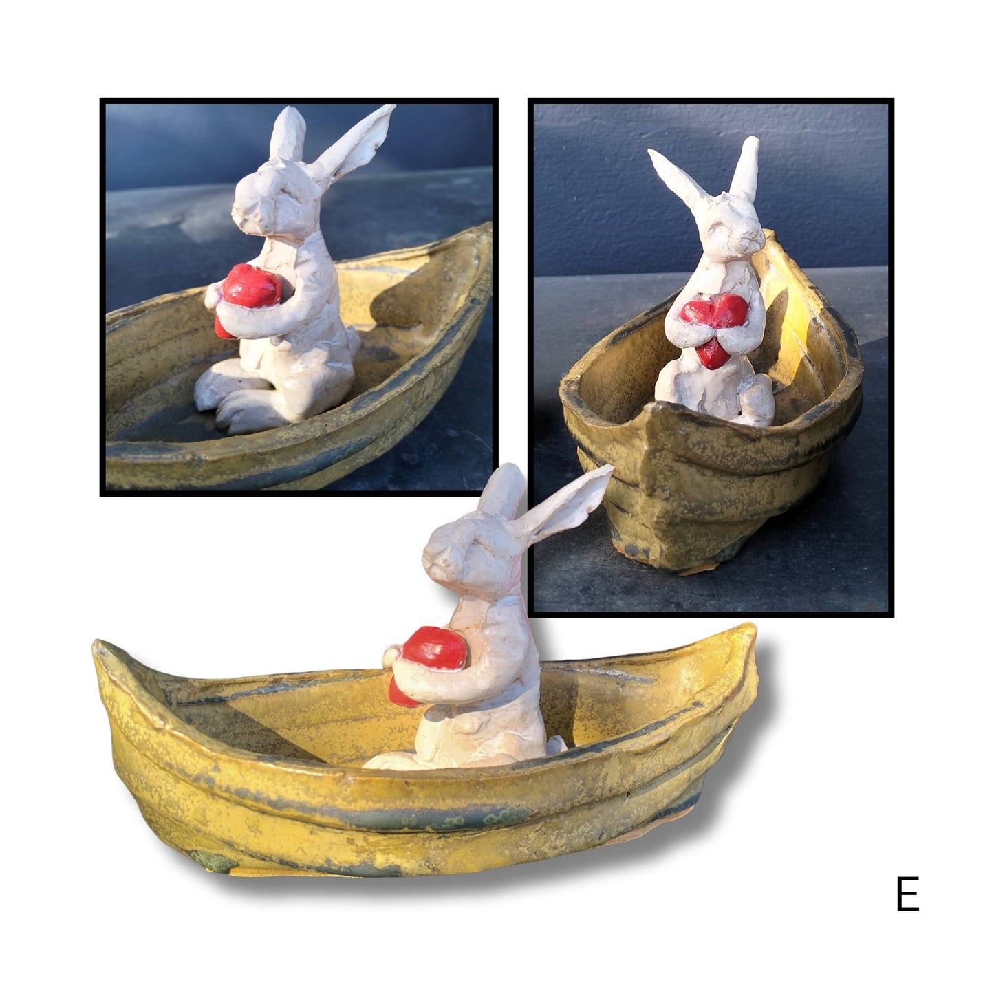 Handmade ceramic Drifter by Kylie Matheson seated in a soft brown boat, gently holding a small red heart with both paws.