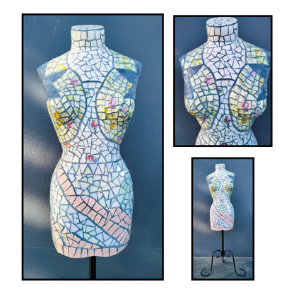 Mosaic female torso sculpture by Janice Corbishley, covered in broken iridescent vintage china plates and cups with floral fragments and dark grout, on black stand
