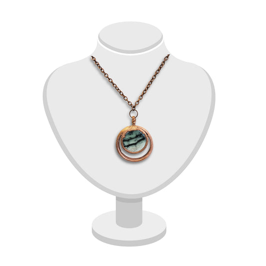 Handmade double loop greenstone pendant with textured copper displayed on white bust.