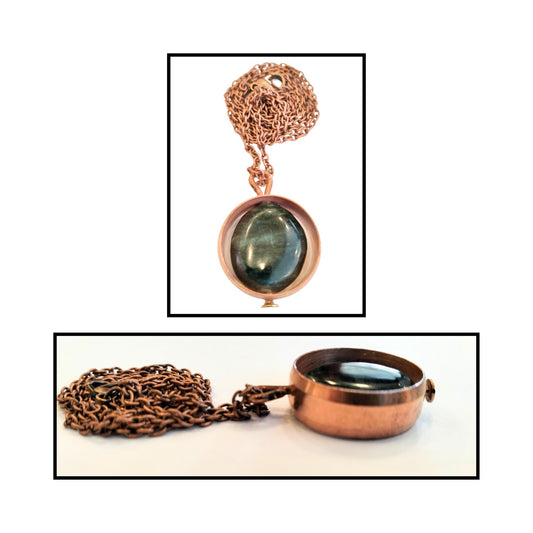 Close-up of oval greenstone bead loosely held inside smooth copper ring.
