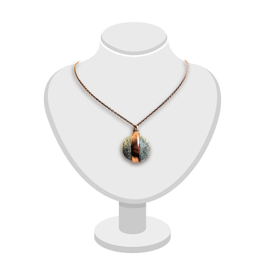 Handcrafted greenstone and copper pendant by Gary Howse displayed on a white bust, showing its organic texture and natural green tones.