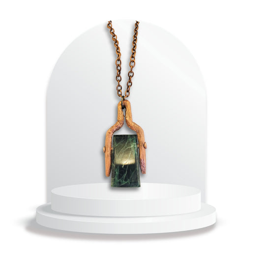 Handmade greenstone pendant with wide copper bale by Gary Howse displayed on a white jewellery stand.