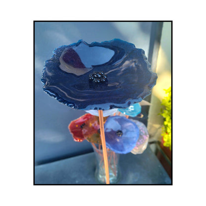 Close-up of a very dark blue glass flower with a dark centre and bent copper stem