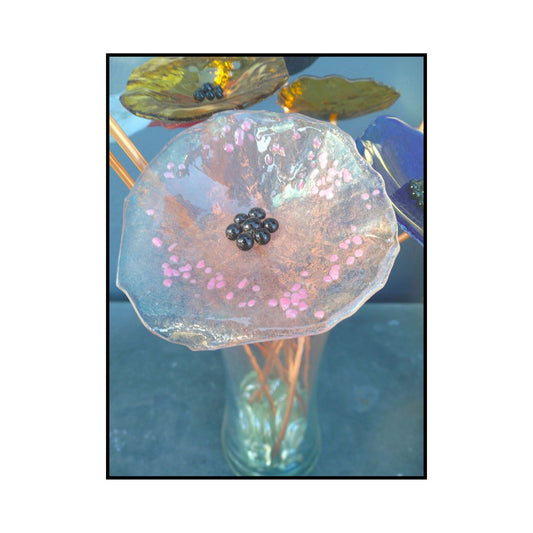 Close-up of a soft pink glass flower with a dark centre and bent copper stem