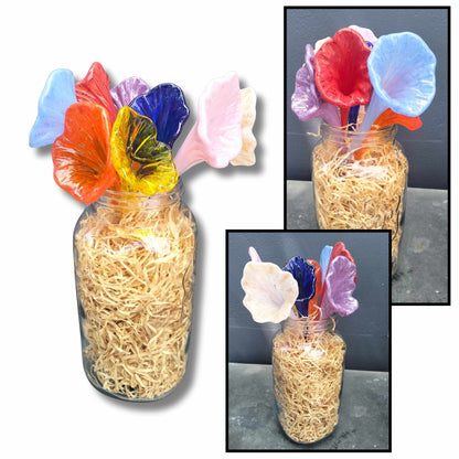 Heather Kremen’s long-stemmed glass flowers in yellow, orange, red, blue, purple, pink and cream, displayed together in a glass jar from several angles.
