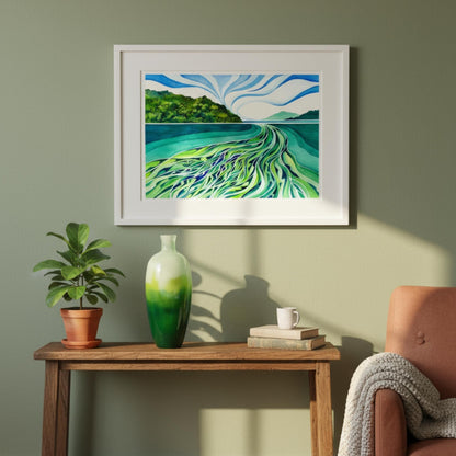 Framed artwork of a landscape with water and mountains on a wall above a wooden table with decor items.