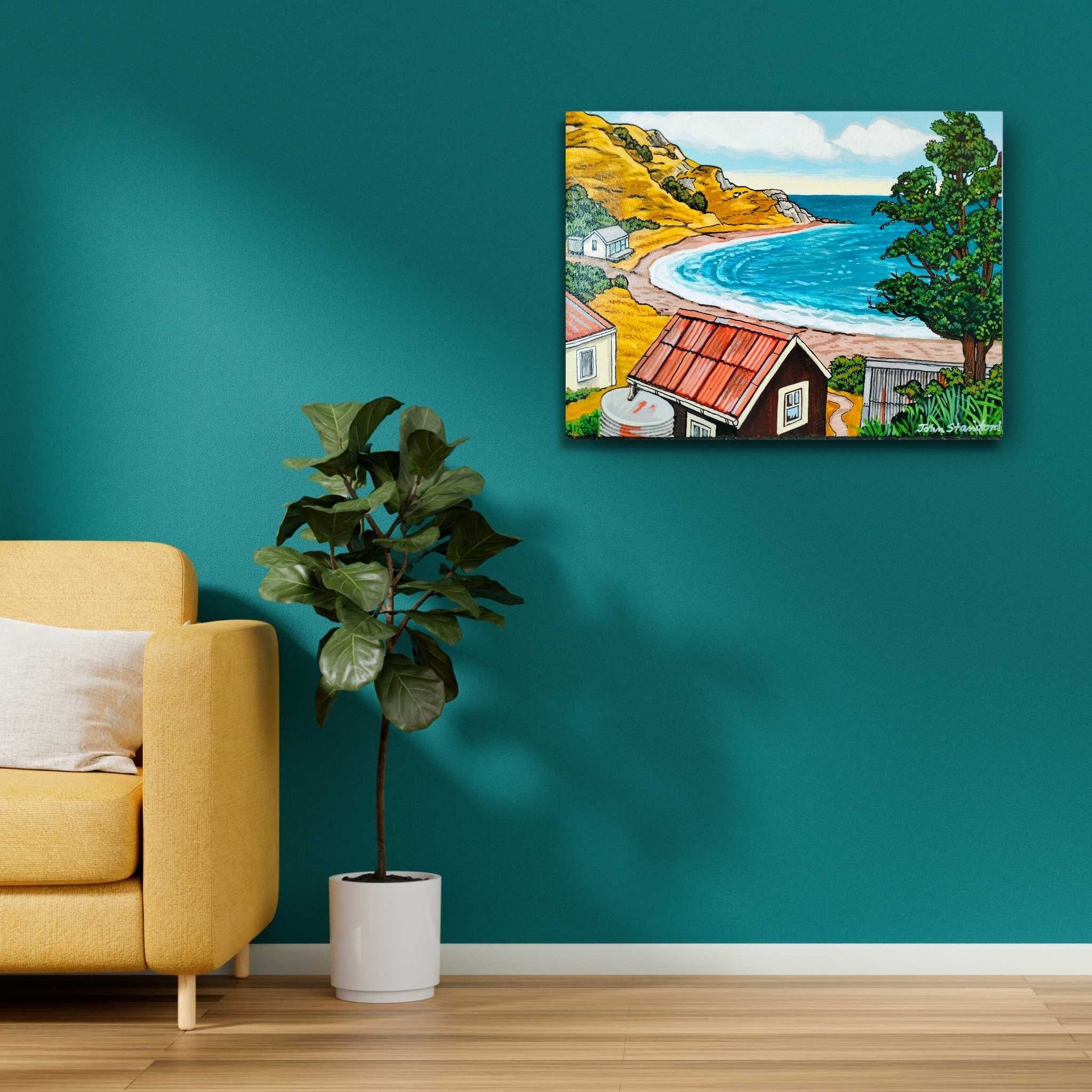 Canvas painting of a coastal scene hanging on a teal wall above a yellow sofa and potted plant.