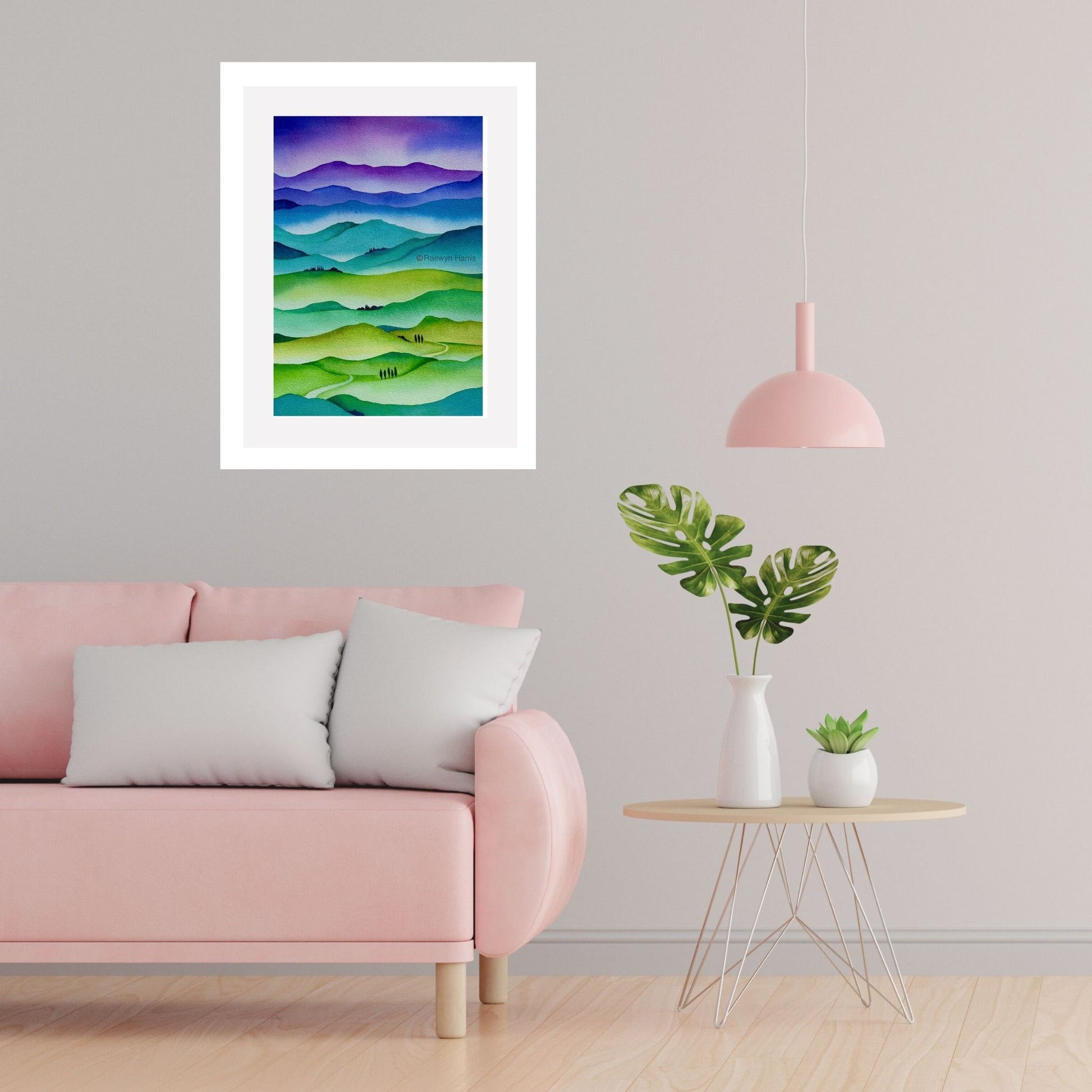 Framed landscape watercolour painting by Raewyn Harris titled "Hills in Harmony" with layered hills in soft greens, blues, and purples in a lounge setting