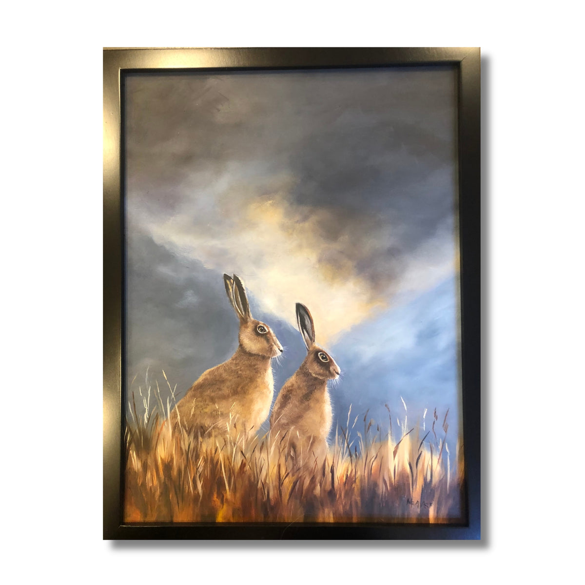 Oil painting of two golden-brown hares sitting alert in long grass under a dramatic stormy sky, by New Zealand artist Marion Aitken
