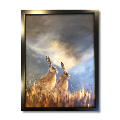 Oil painting of two golden-brown hares sitting alert in long grass under a dramatic stormy sky, by New Zealand artist Marion Aitken
