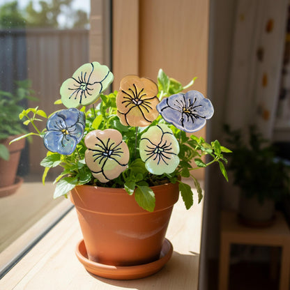 Potted plant with decorative ceramic flowers on a windowsill