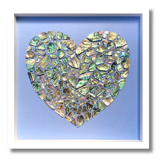 The Paua of Love - heart-shaped artwork made from iridescent paua shells arranged in mosaic pattern on blue background in white frame
