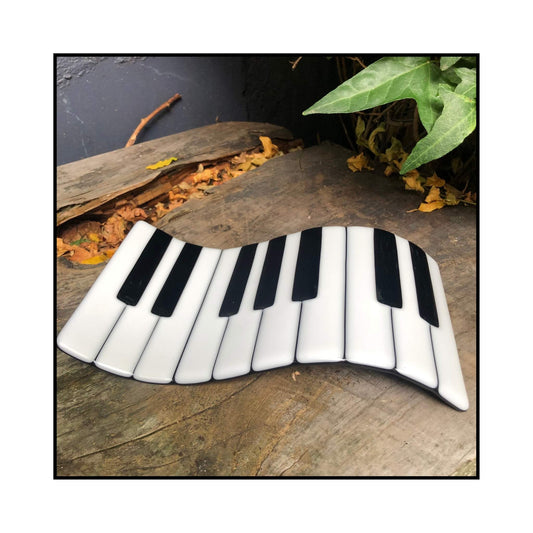 Fused glass piano wave plate with black and white keys in a sculptural S-shape. Handmade by Jill Matthew.