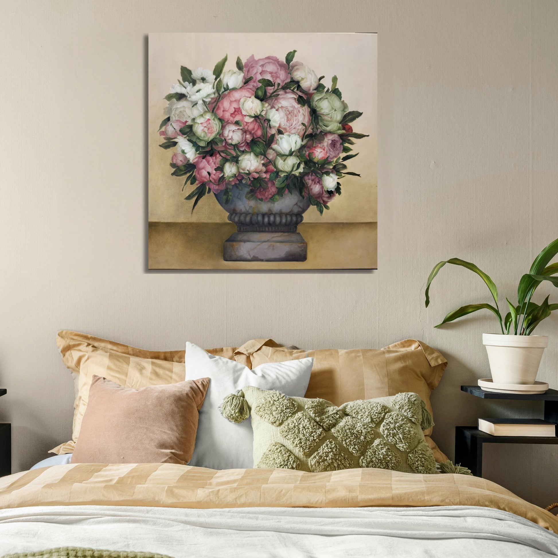 Floral painting above a bed with decorative pillows and a plant.