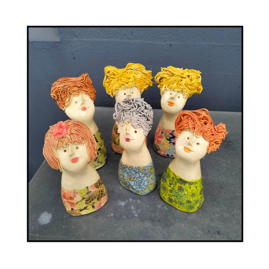Six handcrafted ceramic figurines by Mandy Olson, each with unique poses and colourful outfits, arranged in a playful, characterful lineup known as the Tiny Tarts.