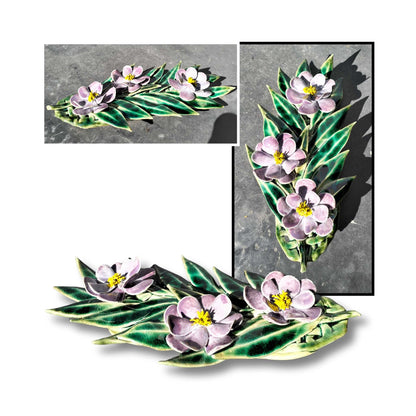 Deep purple ceramic camellia wall art with three flowers and sculpted foliage.