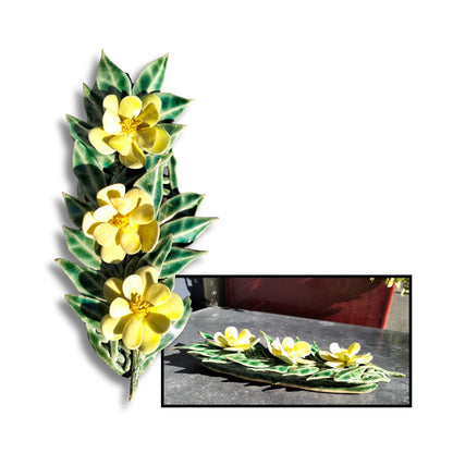 Bright yellow glazed camellia trio on textured leaf base, wall-hanging ceramic.