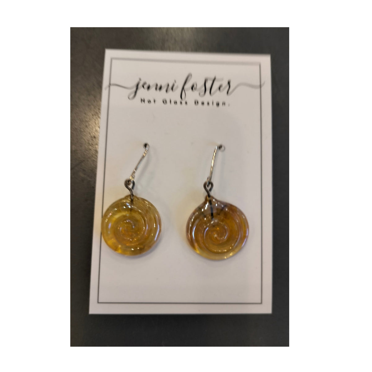 Jenni Foster’s round glass koru earrings in yellow,  displayed on jewellery card.